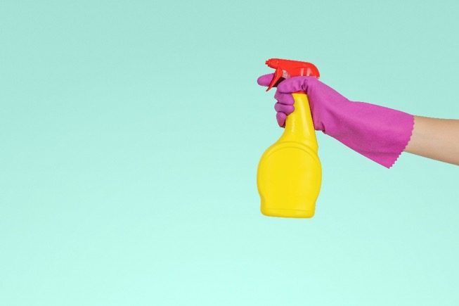 hand with a rubber glove holding a spray bottle