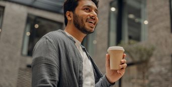 man smiling and holding coffee cup