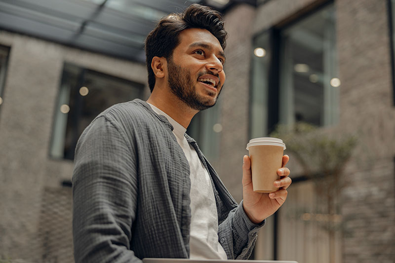 man smiling and holding coffee cup